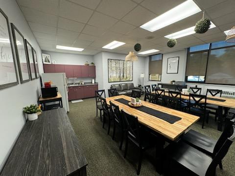 A table with several chairs and a counter and sink in the background